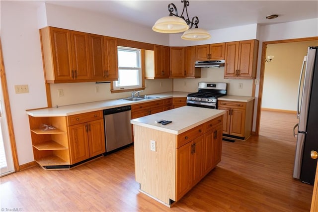 kitchen with appliances with stainless steel finishes, a sink, light wood-style floors, and under cabinet range hood