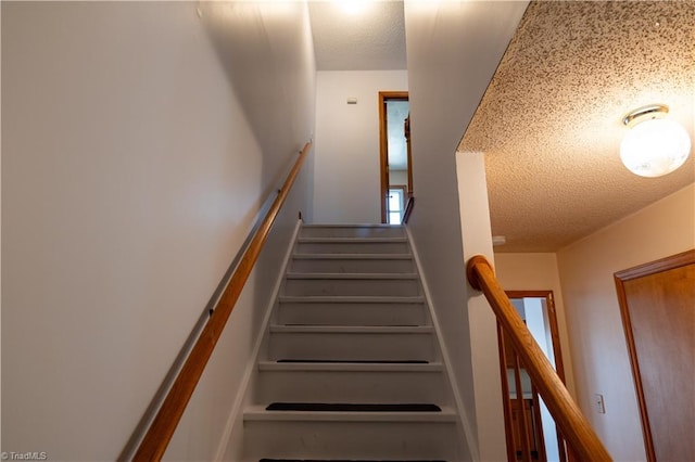 staircase with a textured ceiling