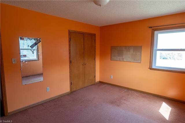 unfurnished bedroom featuring a textured ceiling, a closet, carpet, and baseboards