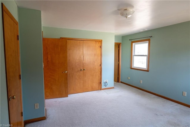 unfurnished bedroom with carpet, a closet, and baseboards