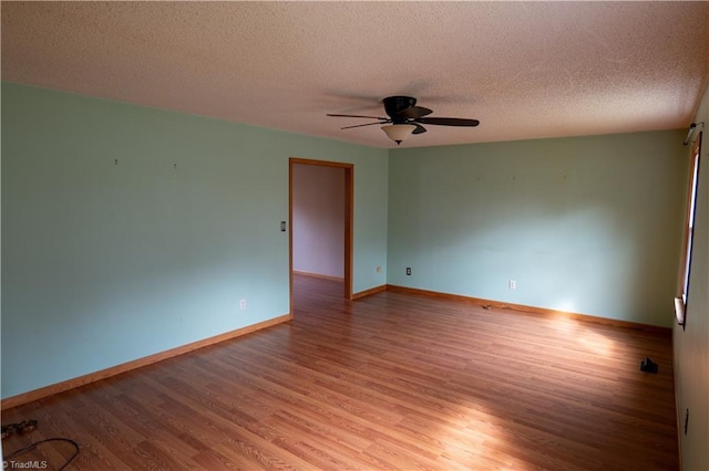 unfurnished room featuring a textured ceiling, light wood finished floors, a ceiling fan, and baseboards