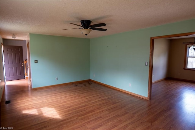 spare room featuring wood finished floors, a ceiling fan, and baseboards