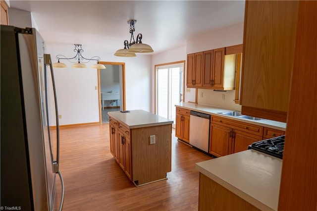 kitchen with stainless steel appliances, a sink, light wood-style floors, light countertops, and a center island