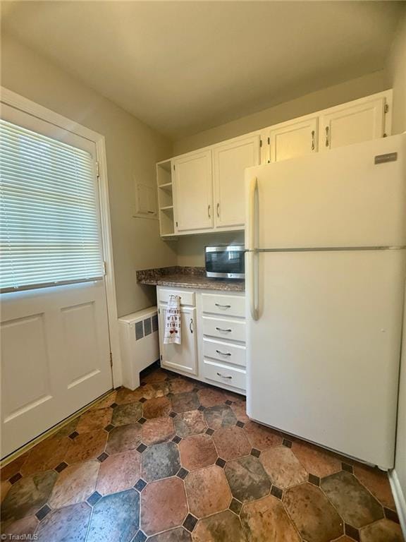 1500 Brent Ct Unit 9-B, Burlington, NC 27215 - kitchen featuring freestanding refrigerator, radiator heating unit, stainless steel microwave, open shelves, and white cabinets
