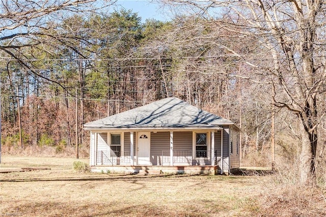 view of front of property with a shingled roof, a front yard, and covered porch