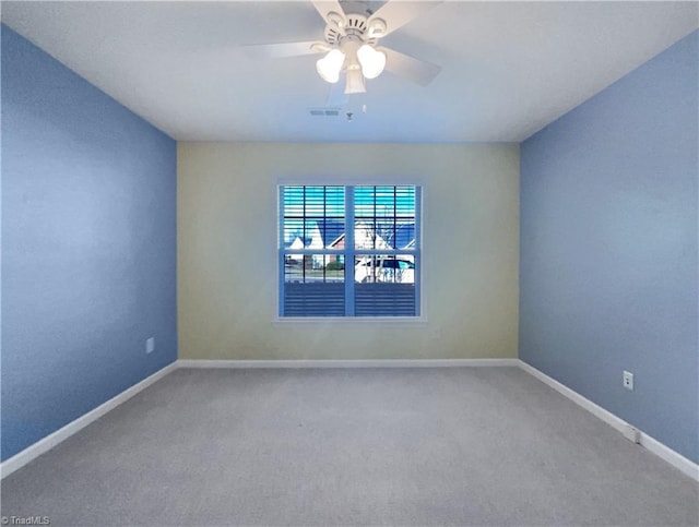 carpeted spare room featuring a ceiling fan, visible vents, and baseboards