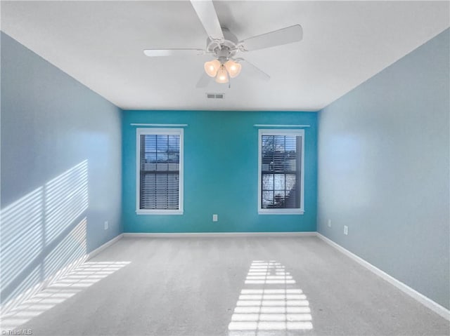 carpeted empty room with baseboards, visible vents, and ceiling fan