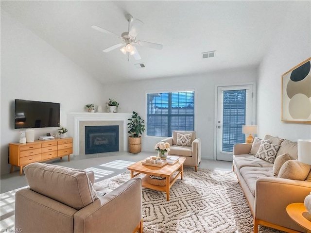 living area with lofted ceiling, a fireplace with flush hearth, visible vents, and ceiling fan