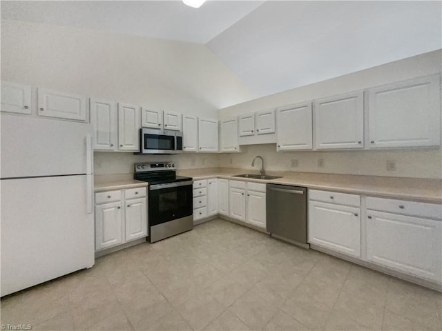 kitchen featuring light countertops, vaulted ceiling, white cabinets, stainless steel appliances, and a sink