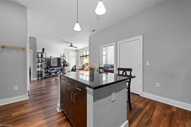 kitchen with a kitchen island, dark hardwood / wood-style floors, dark brown cabinetry, and a kitchen breakfast bar