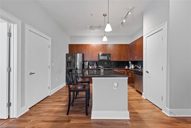 kitchen featuring appliances with stainless steel finishes, tasteful backsplash, light hardwood / wood-style floors, and pendant lighting