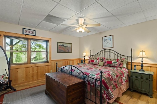 201 Cherokee Cir, Jefferson, NC 28640 - bedroom with light wood finished floors, a wainscoted wall, a paneled ceiling, wood walls, and ceiling fan