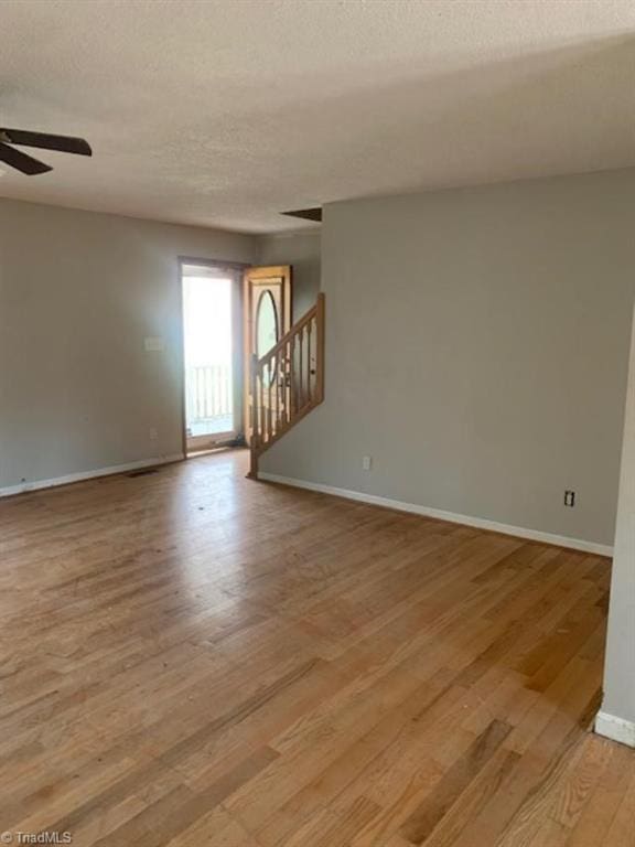 spare room with a textured ceiling, light hardwood / wood-style floors, and ceiling fan