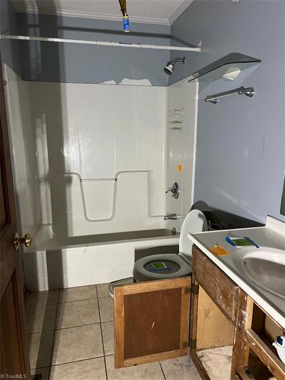 full bathroom featuring tile patterned floors, sink, toilet, ornamental molding, and tub / shower combination