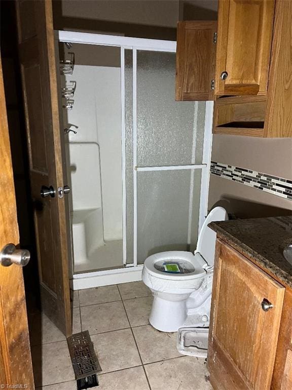 bathroom with tile patterned flooring, vanity, toilet, and a shower with door