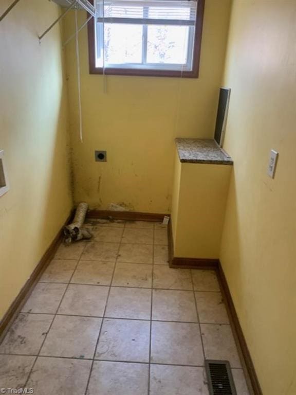 laundry room with electric dryer hookup and light tile patterned flooring