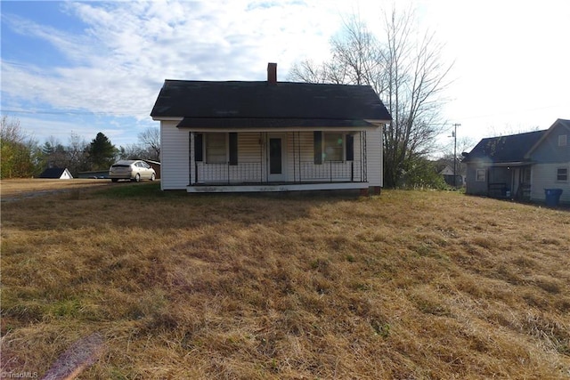 back of house featuring covered porch and a yard