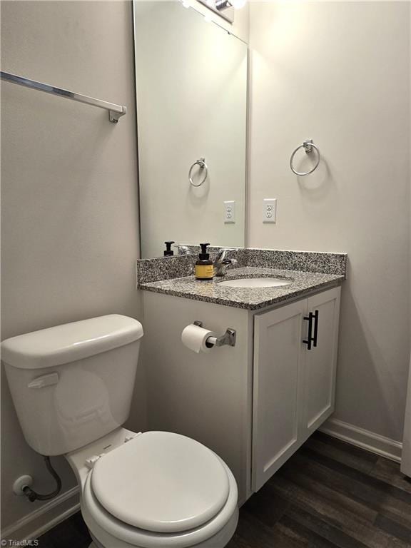 bathroom with toilet, vanity, and hardwood / wood-style flooring