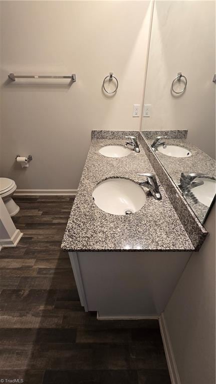 bathroom with toilet, hardwood / wood-style floors, and vanity