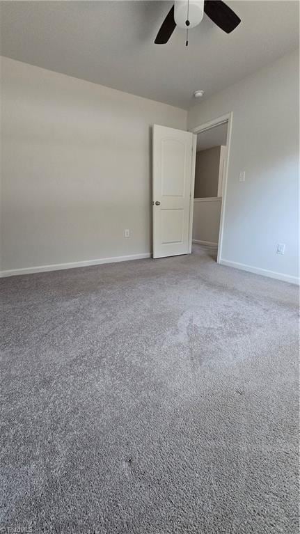 empty room featuring ceiling fan and carpet