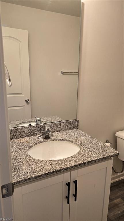 bathroom with hardwood / wood-style flooring, toilet, and vanity