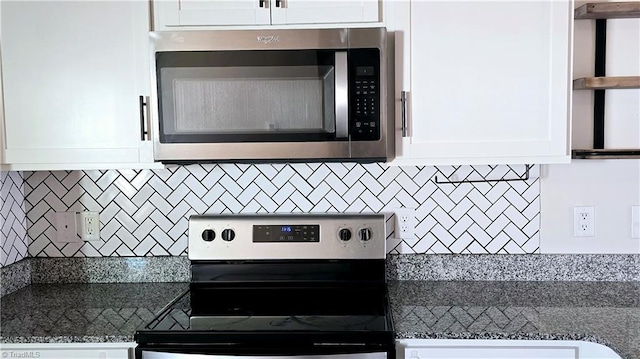 kitchen with appliances with stainless steel finishes, dark stone countertops, backsplash, and white cabinetry