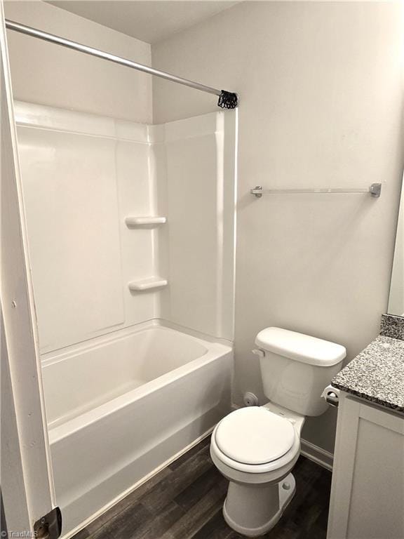 full bathroom with hardwood / wood-style flooring, washtub / shower combination, vanity, and toilet