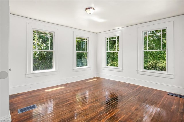 spare room featuring hardwood / wood-style floors and plenty of natural light