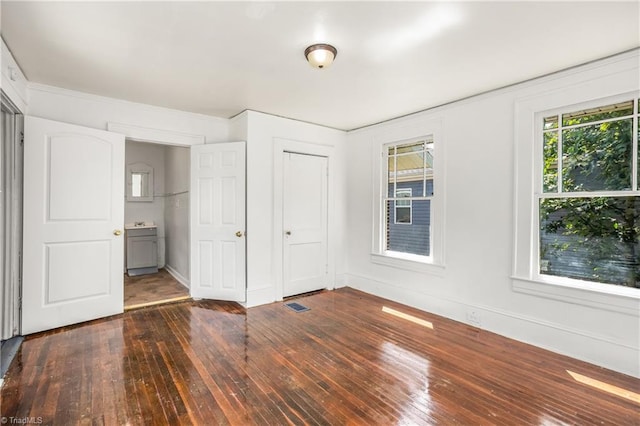 unfurnished bedroom featuring connected bathroom and hardwood / wood-style flooring