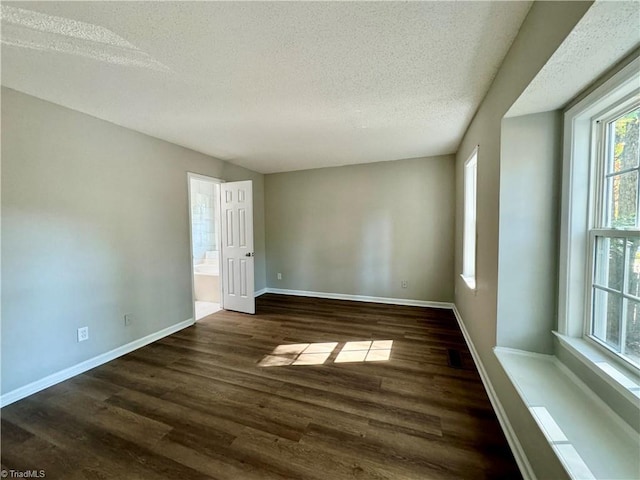 unfurnished room with a textured ceiling, wood finished floors, and baseboards