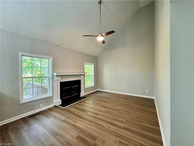 unfurnished living room with a ceiling fan, wood finished floors, baseboards, a fireplace with raised hearth, and high vaulted ceiling