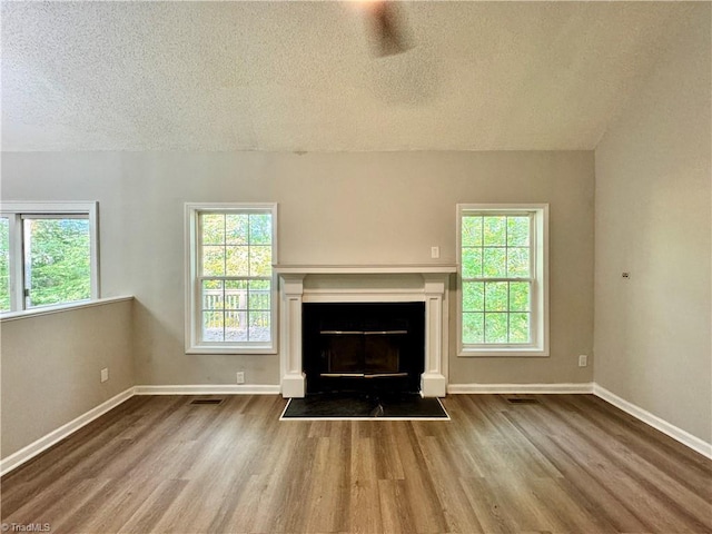 unfurnished living room featuring a textured ceiling, wood finished floors, a fireplace, and baseboards