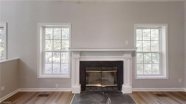 detailed view of wood finished floors, a fireplace with flush hearth, and baseboards