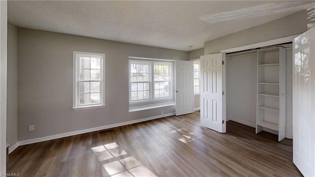 unfurnished bedroom with a textured ceiling, wood finished floors, baseboards, and a closet