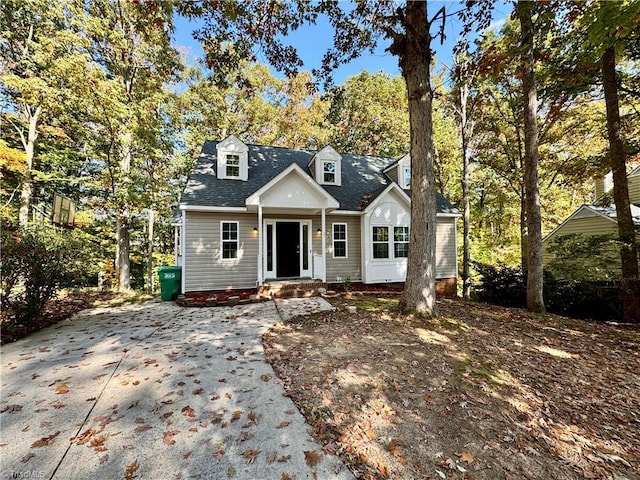 new england style home with roof with shingles