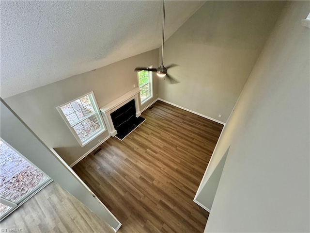 unfurnished living room with a textured ceiling, dark hardwood / wood-style floors, high vaulted ceiling, and ceiling fan