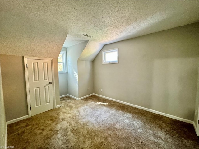 additional living space featuring carpet floors, lofted ceiling, a textured ceiling, and baseboards