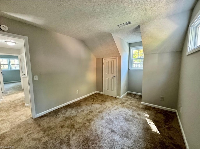 bonus room with carpet, a textured ceiling, baseboards, and vaulted ceiling