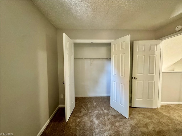 unfurnished bedroom featuring carpet, a closet, a textured ceiling, and baseboards