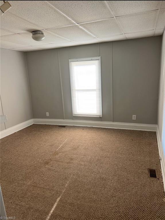 carpeted spare room with a drop ceiling