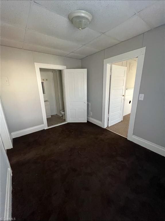 unfurnished bedroom with ensuite bath and a drop ceiling