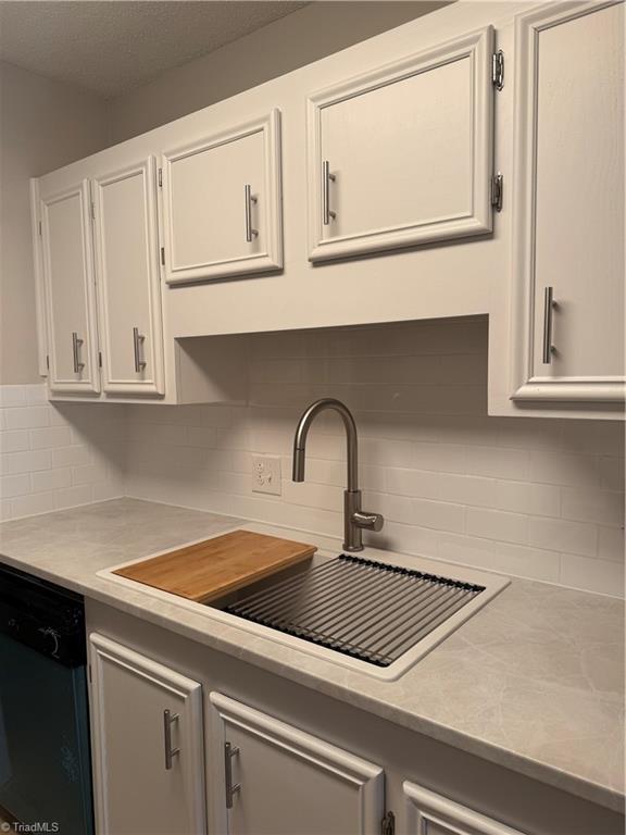 kitchen with white cabinetry, sink, decorative backsplash, and dishwasher