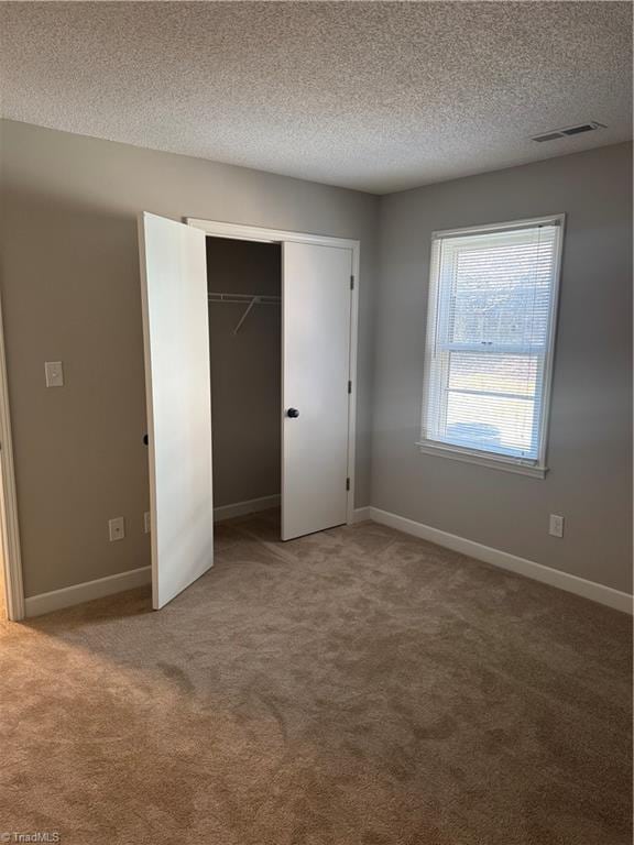 unfurnished bedroom with carpet flooring, a textured ceiling, and a closet