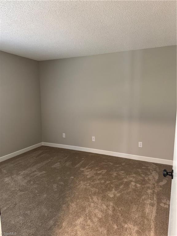 unfurnished room featuring dark carpet and a textured ceiling