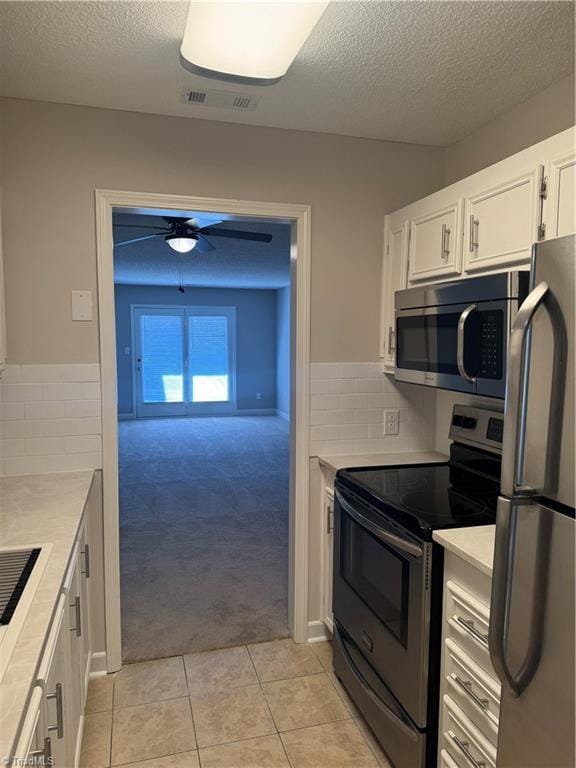 kitchen featuring light tile patterned flooring, appliances with stainless steel finishes, tasteful backsplash, white cabinets, and ceiling fan