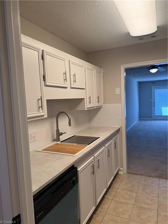 kitchen with white cabinetry, sink, light tile patterned floors, and stainless steel dishwasher