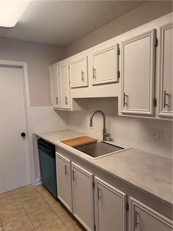 kitchen with white cabinetry, black dishwasher, sink, and light tile patterned floors