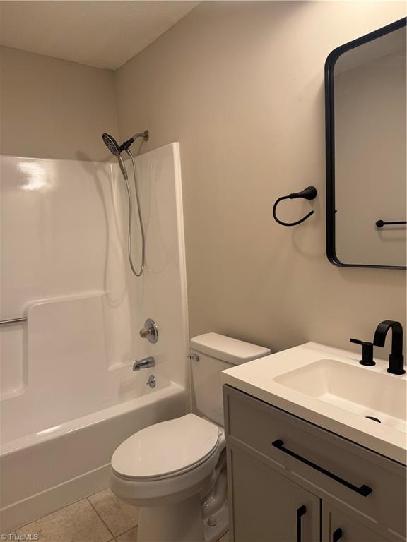 full bathroom with tile patterned floors, toilet,  shower combination, and vanity