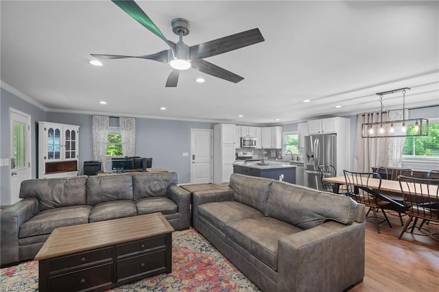 living area featuring light wood-type flooring, crown molding, ceiling fan, and recessed lighting