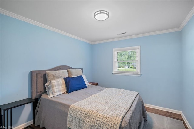 bedroom featuring crown molding, wood finished floors, visible vents, and baseboards